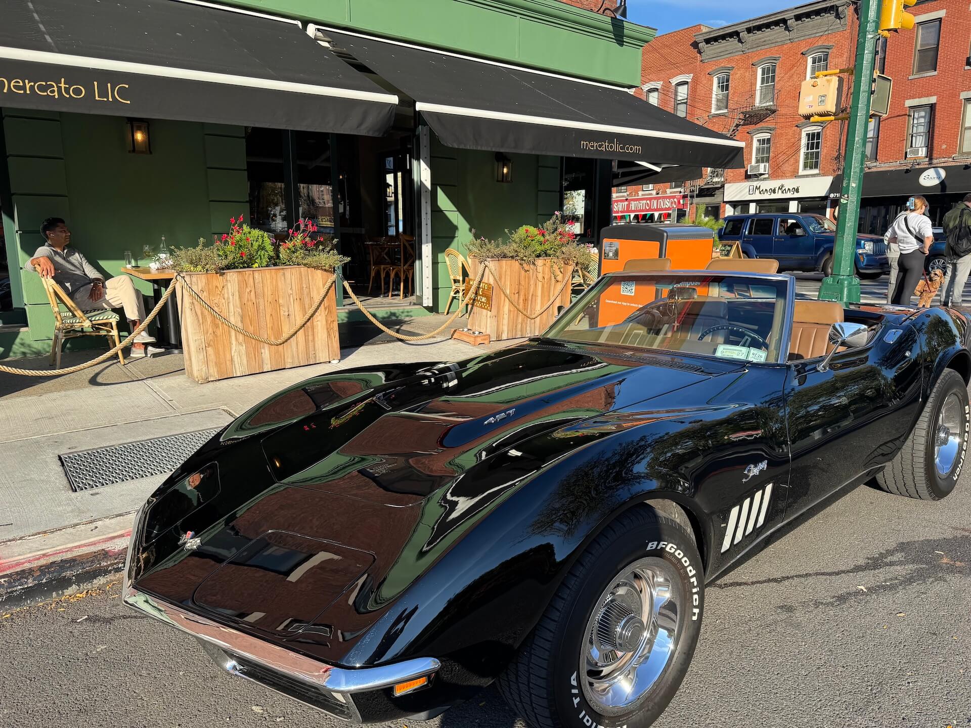 A black classic convertible parked at the curb outside the restaurant