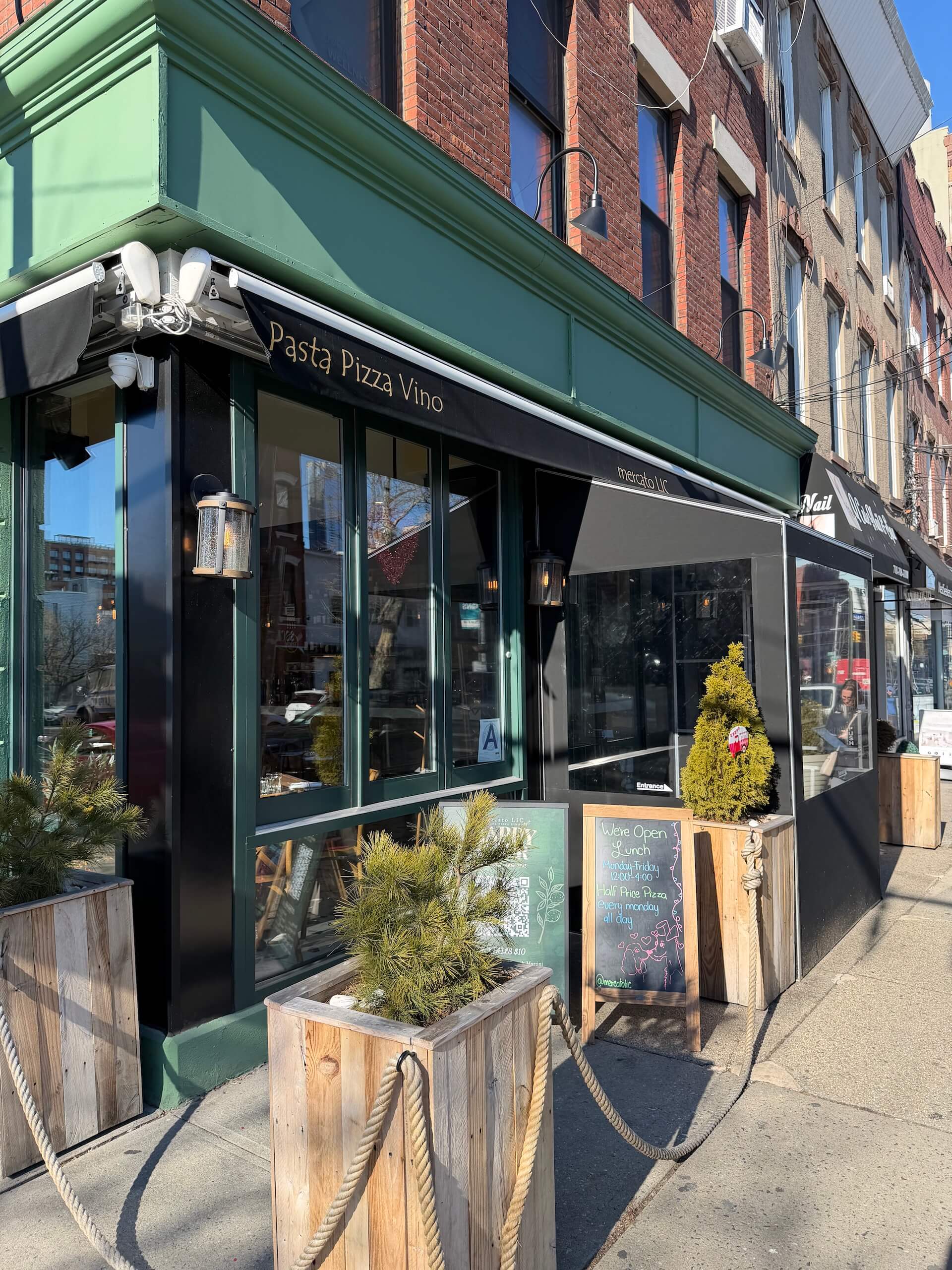 The corner storefront with planter boxes and a rope along the sidewalk
